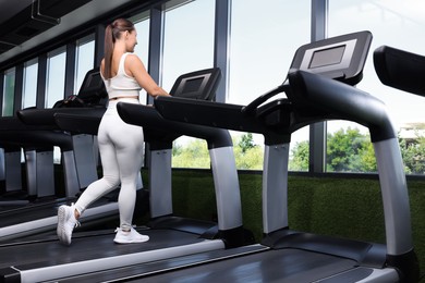 Photo of Athletic woman training on treadmill in gym, low angle view