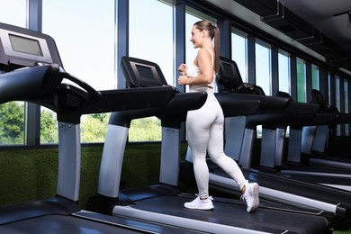 Photo of Athletic woman training on treadmill in gym, low angle view