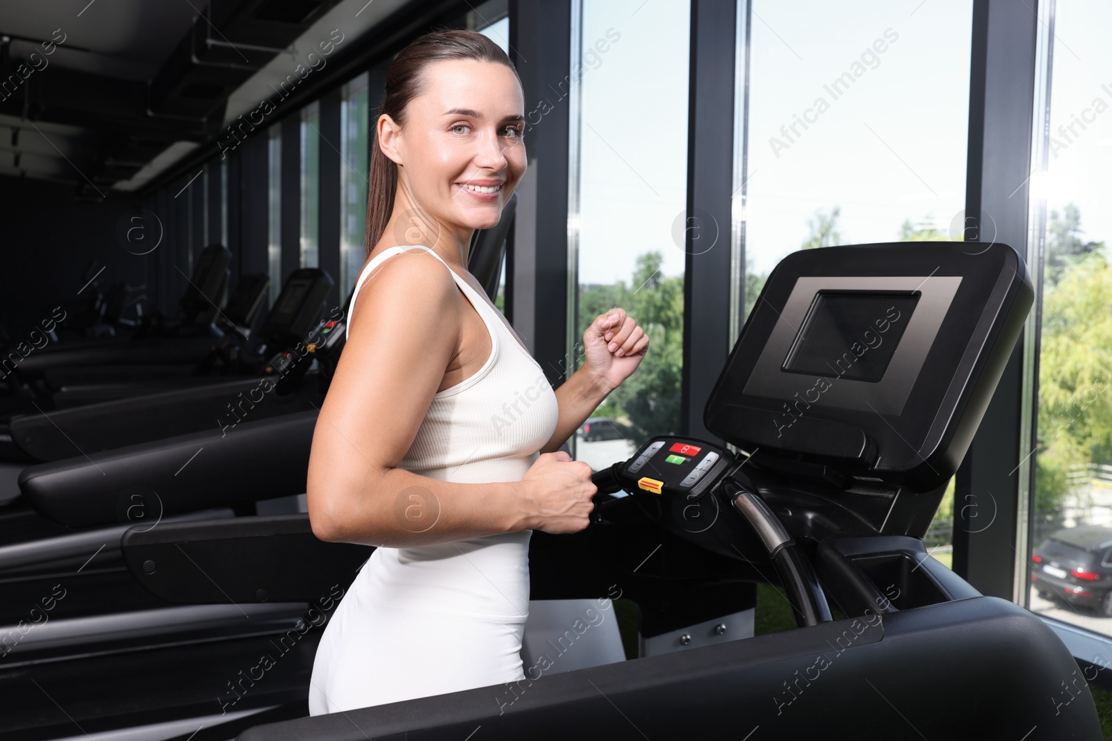 Photo of Smiling woman training on treadmill in gym
