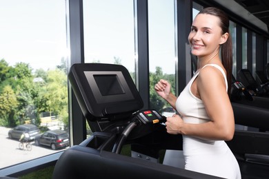 Photo of Smiling woman training on treadmill in gym