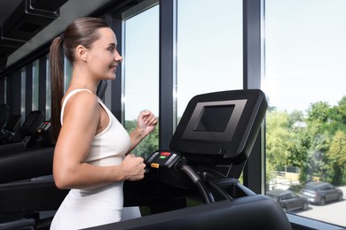 Photo of Smiling woman training on treadmill in gym