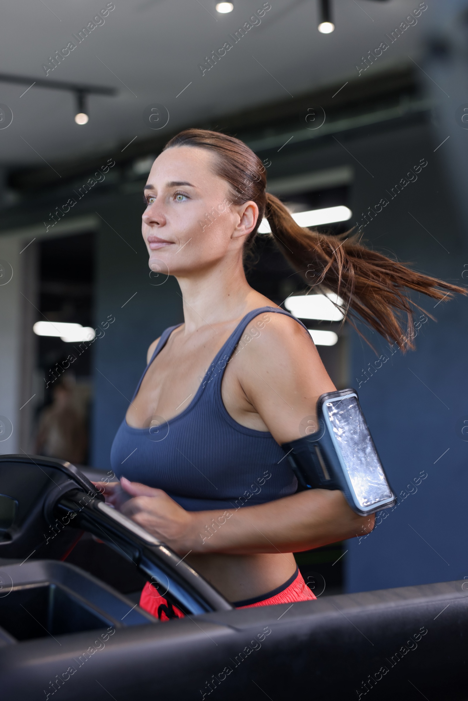 Athletic woman with armband training on treadmill in gym Photo of Athletic woman with armband training on treadmill in gym