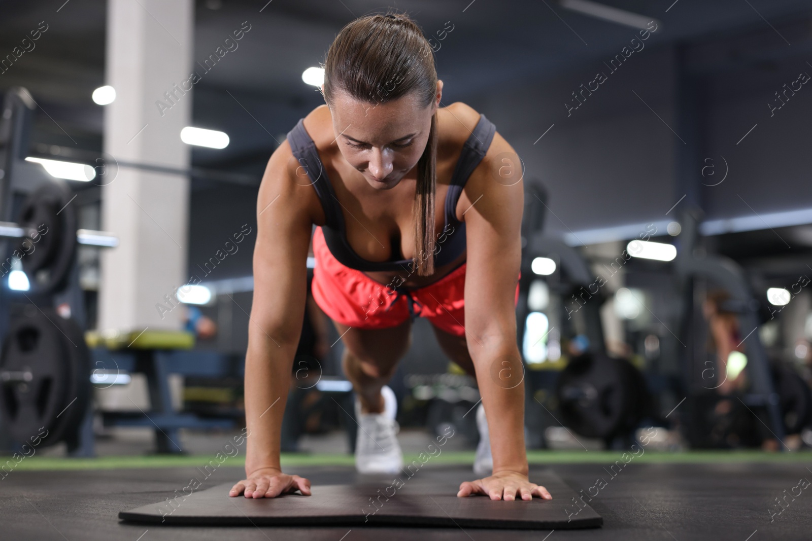 Athletic woman doing plank exercise on yoga mat in gym Photo of Athletic woman doing plank exercise on yoga mat in gym