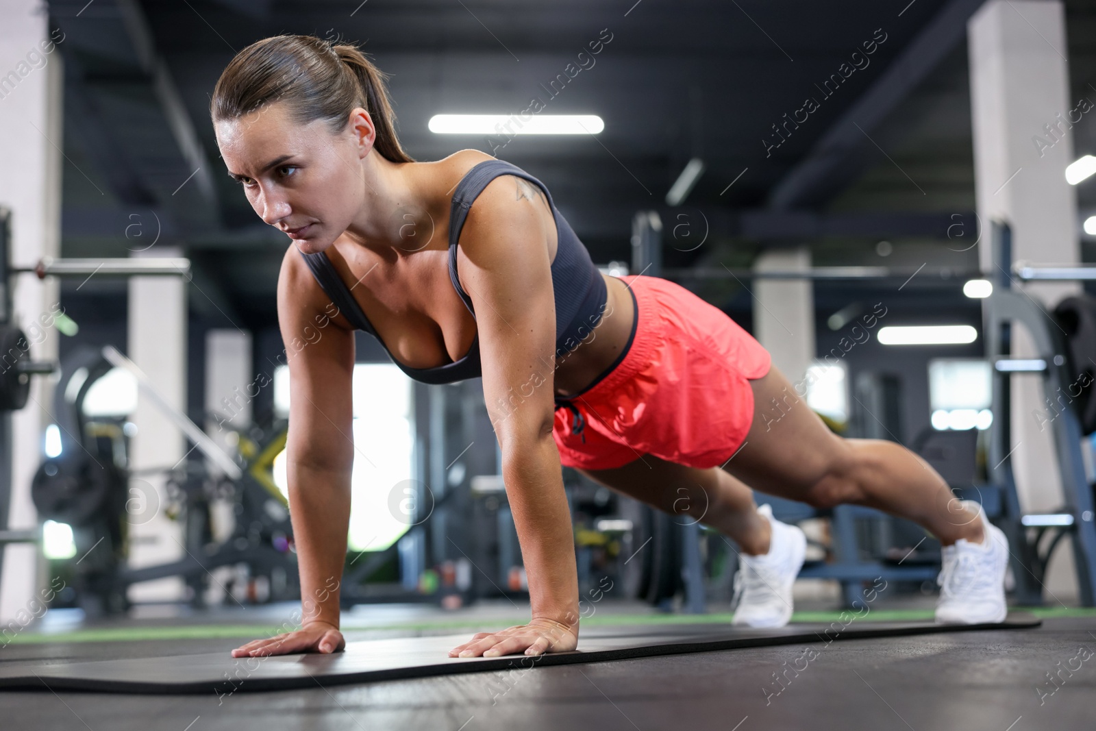 Athletic woman doing plank exercise on yoga mat in gym Photo of Athletic woman doing plank exercise on yoga mat in gym