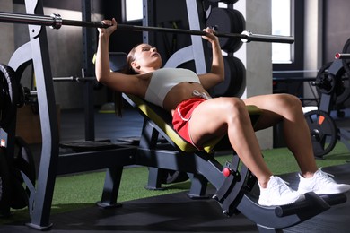 Photo of Athletic woman training with barbell in gym