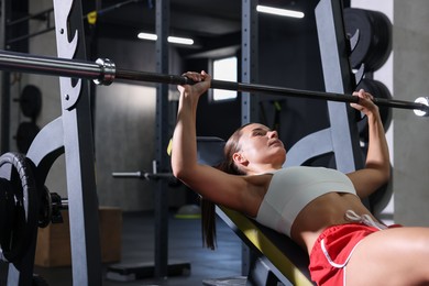 Photo of Athletic woman training with barbell in gym