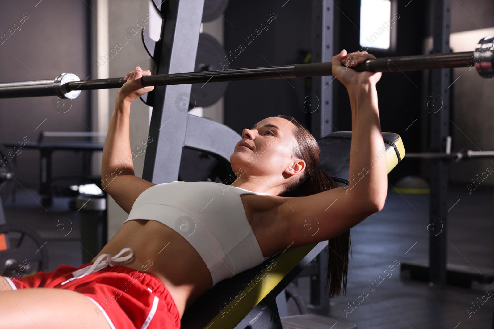 Photo of Athletic woman training with barbell in gym