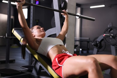 Photo of Athletic woman training with barbell in gym