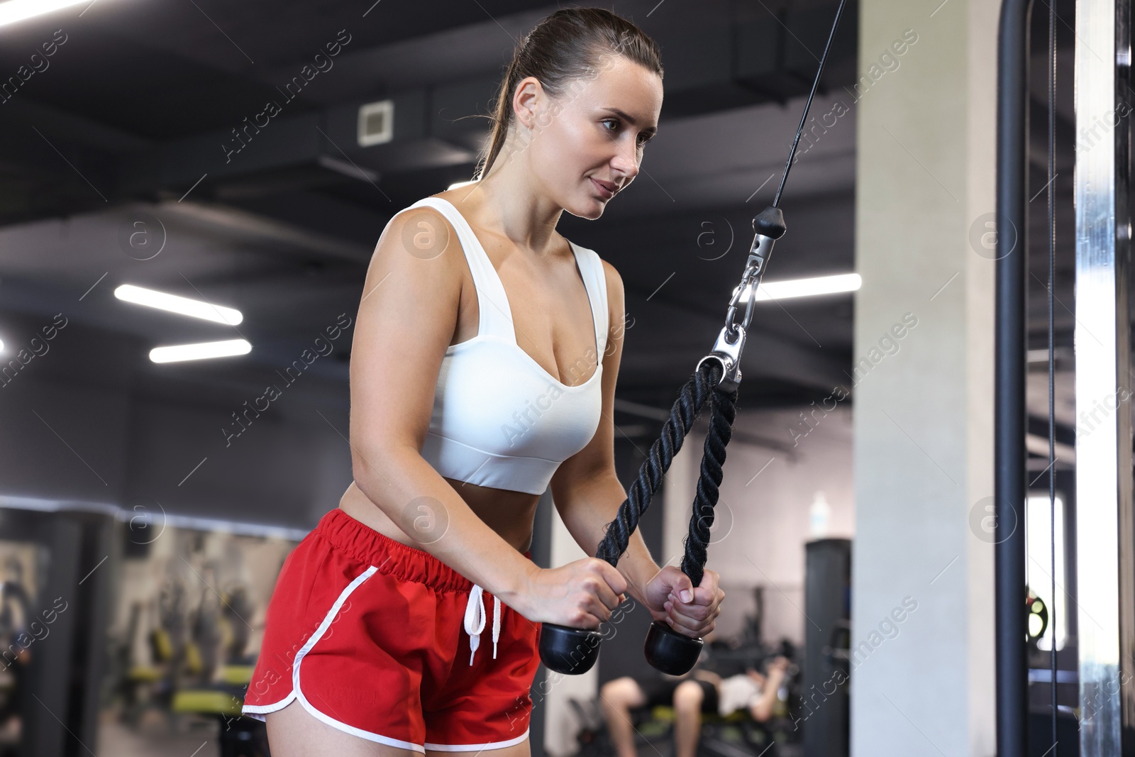 Athletic woman training on pulley machine in gym Photo of Athletic woman training on pulley machine in gym