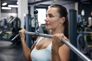 Photo of Athletic woman training on lat pulldown machine in gym