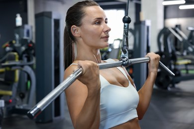 Photo of Athletic woman training on lat pulldown machine in gym