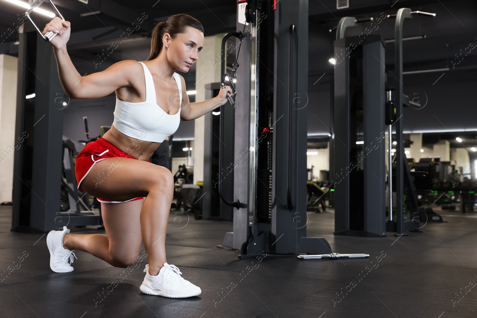 Photo of Athletic woman training on cable crossover machine in gym. Space for text