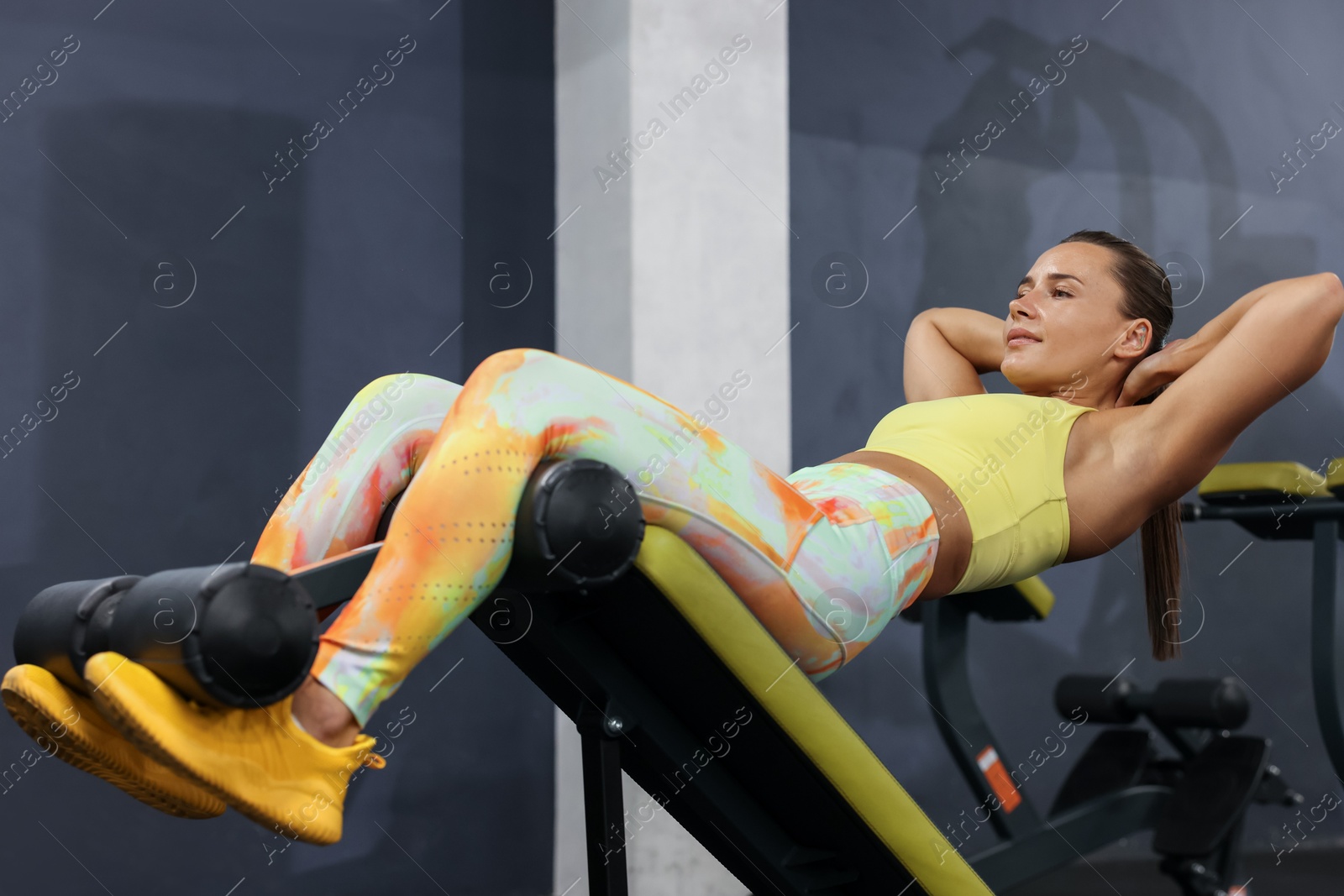 Photo of Athletic woman training on roman chair in gym