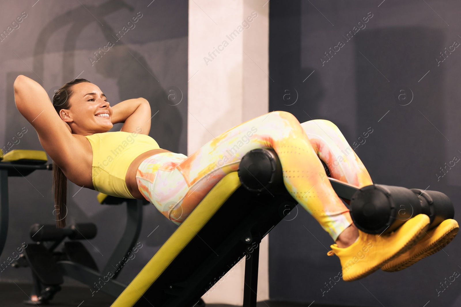 Smiling woman training on roman chair in gym Photo of Smiling woman training on roman chair in gym
