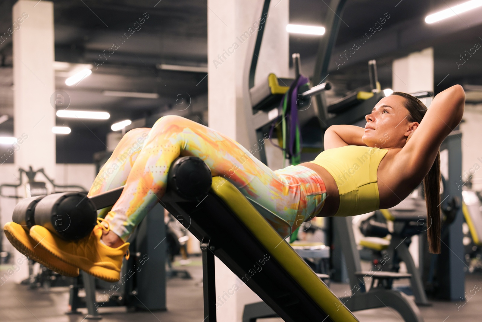 Photo of Athletic woman training on roman chair in gym