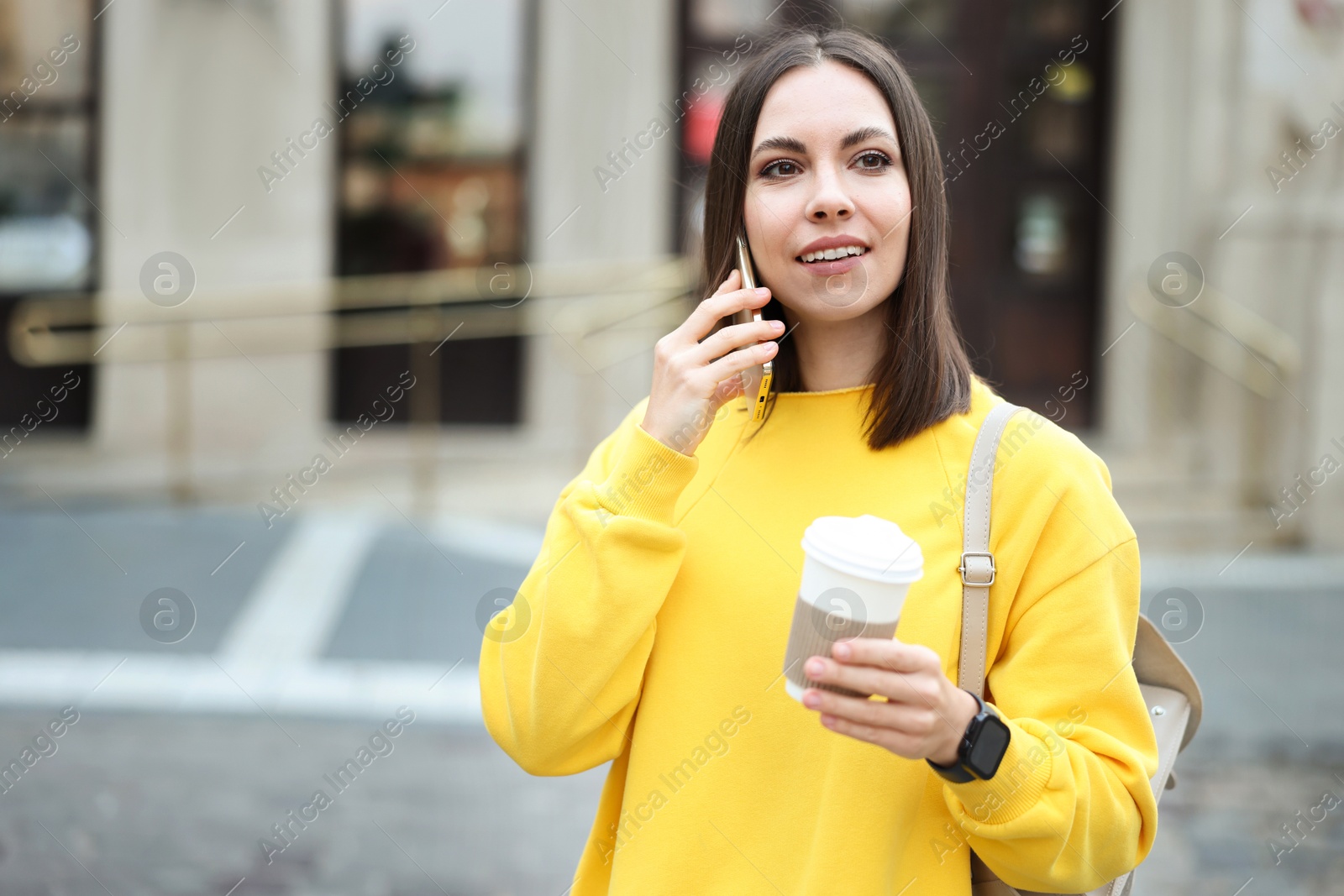 Photo of Coffee to go. Woman with paper cup of drink talking on smartphone outdoors, space for text