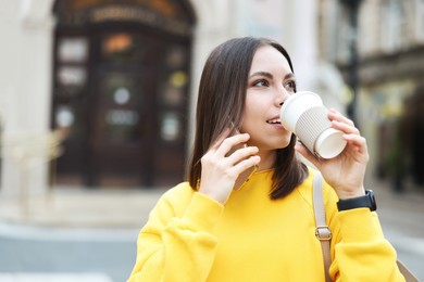 Photo of Coffee to go. Woman with paper cup of drink talking on smartphone outdoors, space for text