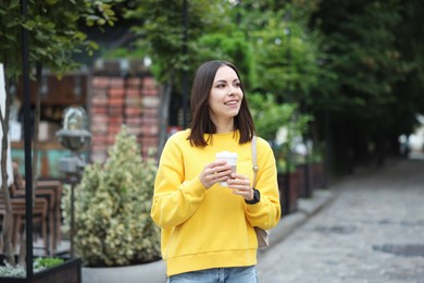 Photo of Coffee to go. Woman with paper cup of drink on city street