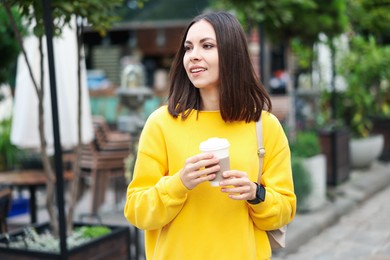 Photo of Coffee to go. Woman with paper cup of drink on city street