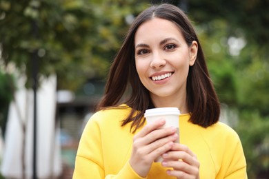 Photo of Coffee to go. Woman with paper cup of drink on city street, space for text