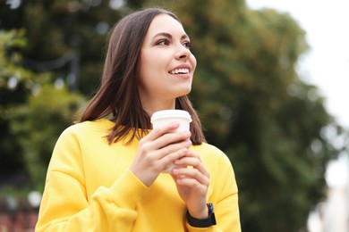 Photo of Coffee to go. Woman with paper cup of drink on city street, space for text