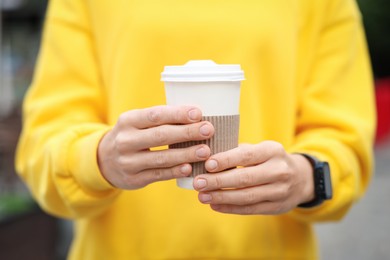 Photo of Coffee to go. Woman with paper cup of drink on city street, closeup