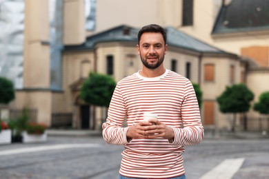 Photo of Coffee to go. Man with paper cup of drink on city street, space for text