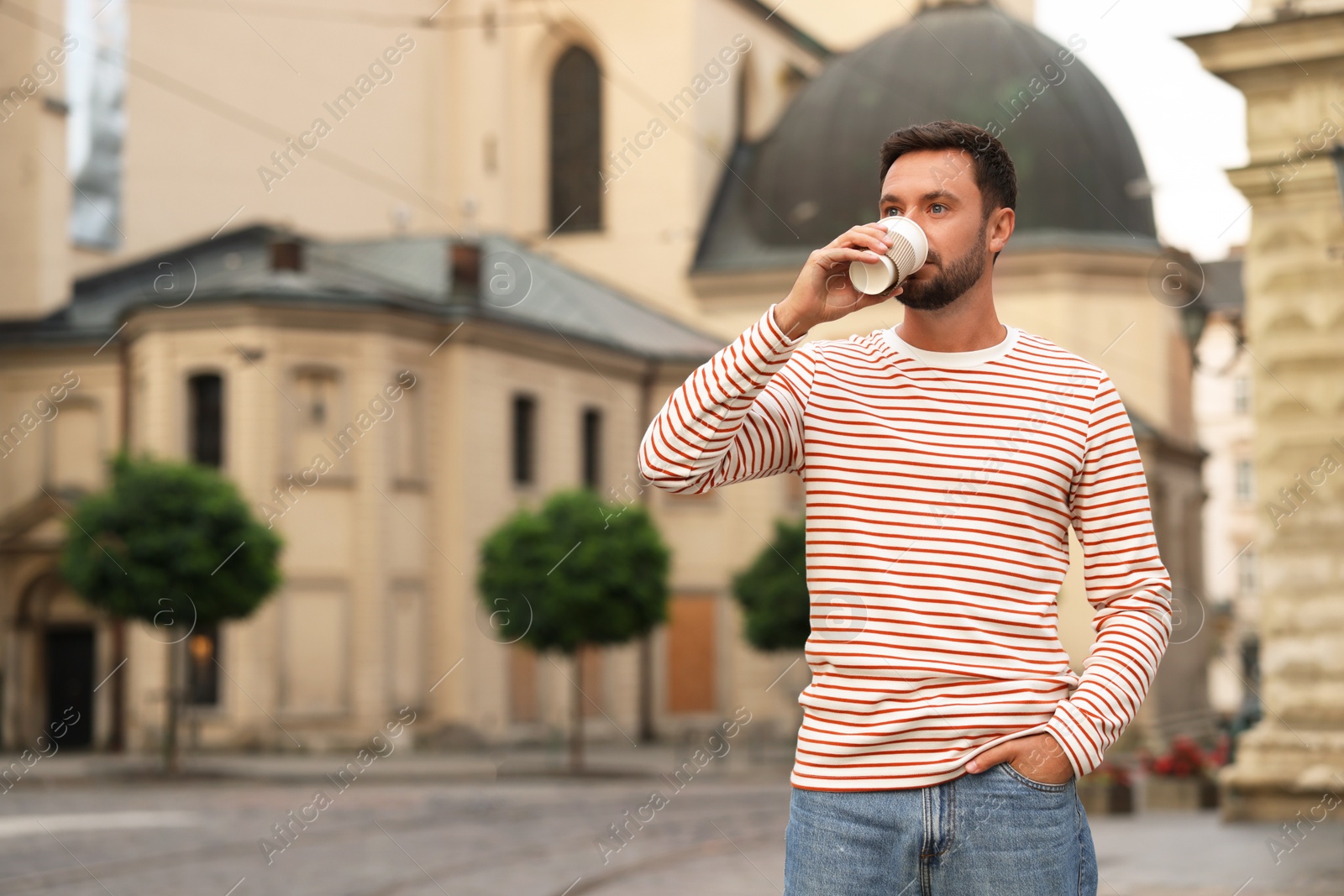 Photo of Coffee to go. Man with paper cup of drink on city street, space for text