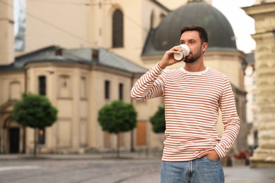 Photo of Coffee to go. Man with paper cup of drink on city street, space for text