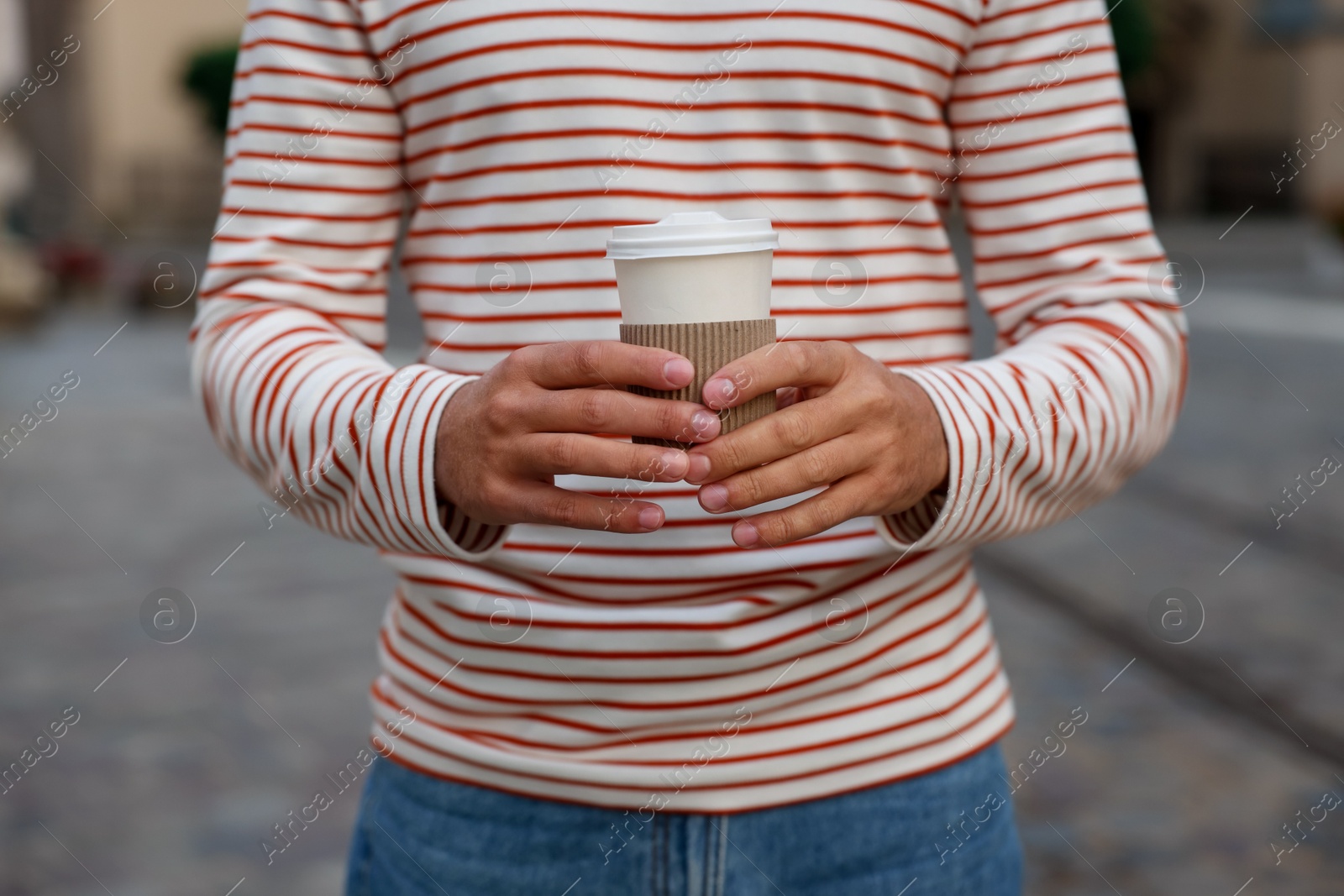 Photo of Coffee to go. Man with paper cup of drink on city street, closeup