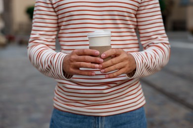 Photo of Coffee to go. Man with paper cup of drink on city street, closeup