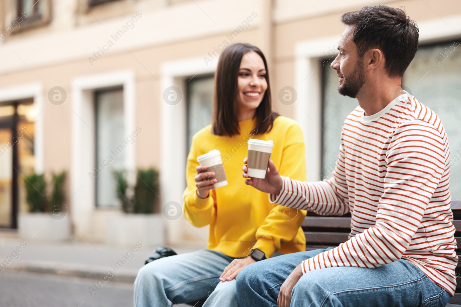 Photo of Coffee to go. Couple with paper cups of drinks on city street, space for text