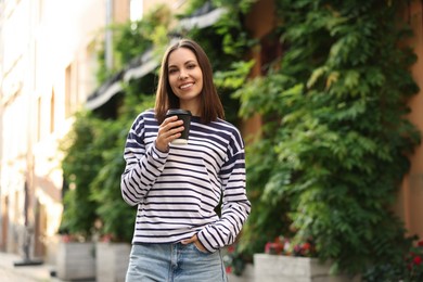 Photo of Coffee to go. Woman with paper cup of drink outdoors, space for text