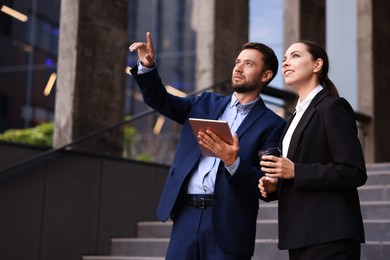 Photo of Coffee to go. Woman with paper cup of drink and her business partner during meeting outdoors, space for text