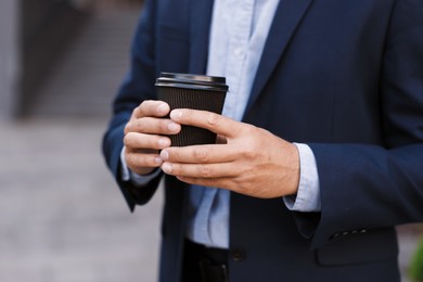 Photo of Coffee to go. Man with paper cup of drink outdoors, closeup. Space for text