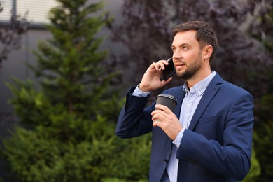 Photo of Coffee to go. Man with paper cup of drink talking on smartphone outdoors, space for text