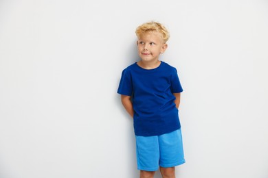 Photo of Cute little boy standing against white background. Space for text