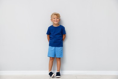 Photo of Cute little boy standing near light wall