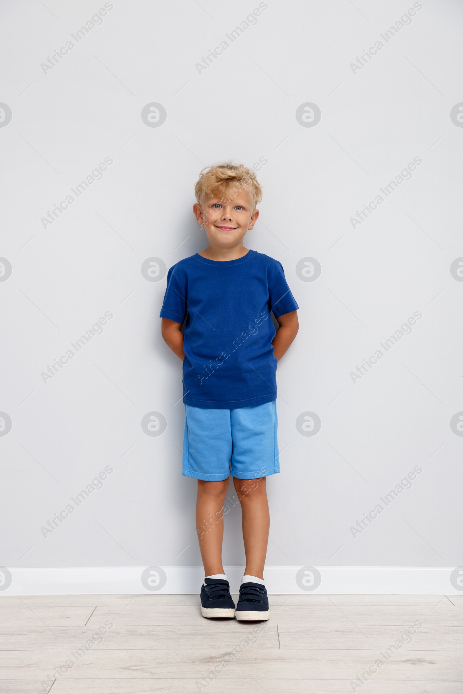 Photo of Cute little boy standing near white wall