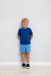 Photo of Cute little boy standing near white wall