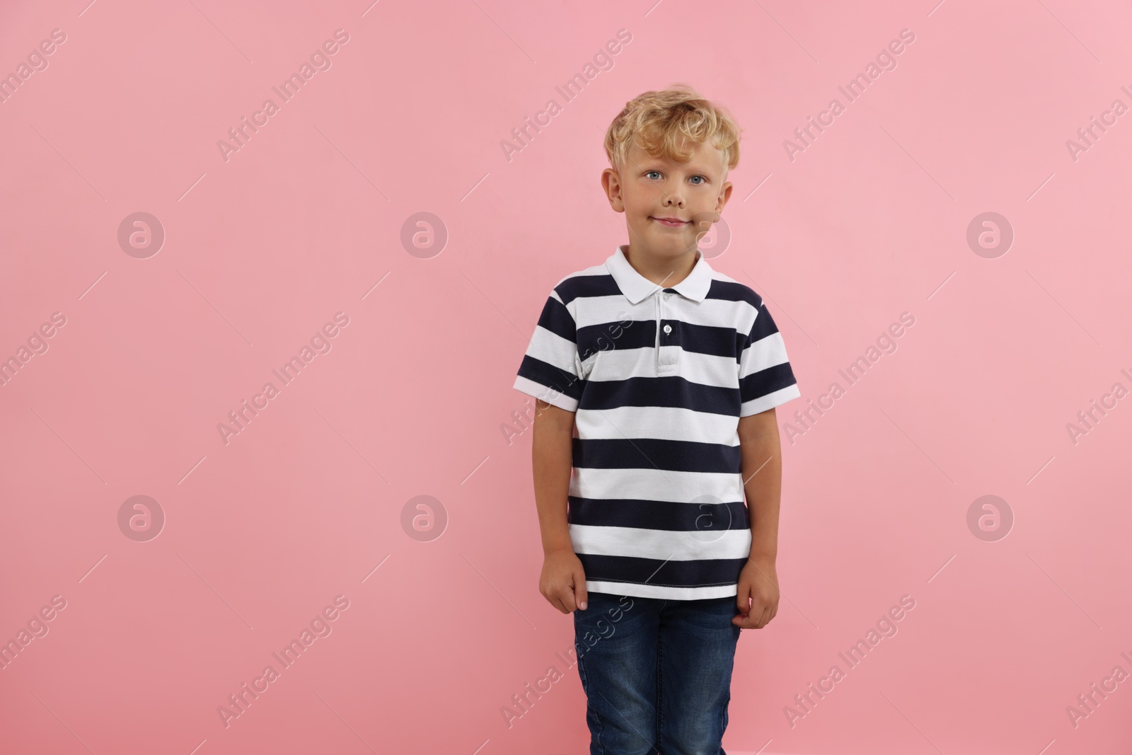 Photo of Cute little boy standing near pink background