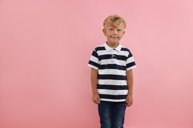 Photo of Cute little boy standing near pink background