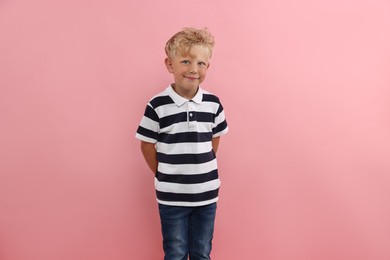 Photo of Cute little boy standing near pink background