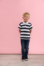 Photo of Cute little boy standing near pink wall