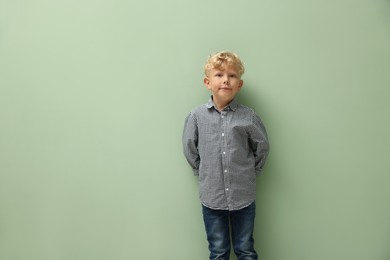 Photo of Cute little boy standing near green background. Space for text