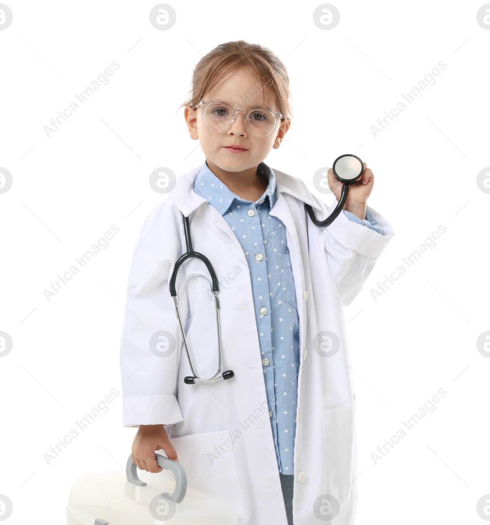 Photo of Choice of profession. Little girl in uniform with stethoscope and case pretending to be doctor on white background