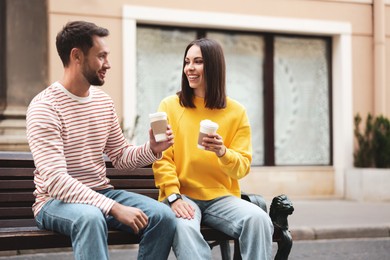 Photo of Coffee to go. Couple with paper cups of drinks on city street, space for text