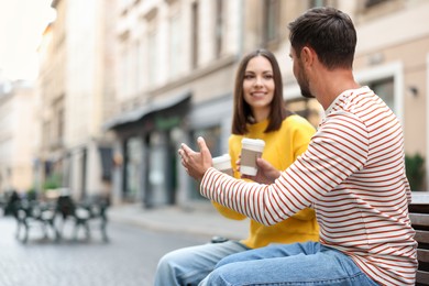 Photo of Coffee to go. Couple with paper cups of drinks on city street, selective focus. Space for text