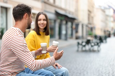 Photo of Coffee to go. Couple with paper cups of drinks on city street, selective focus. Space for text