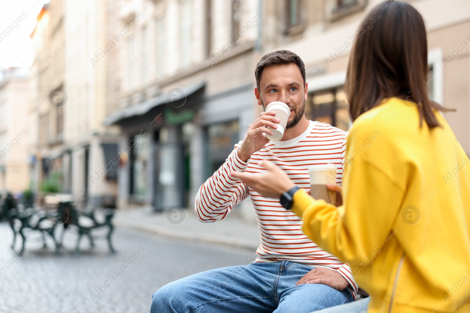 Photo of Coffee to go. Couple with paper cups of drinks on city street, selective focus. Space for text